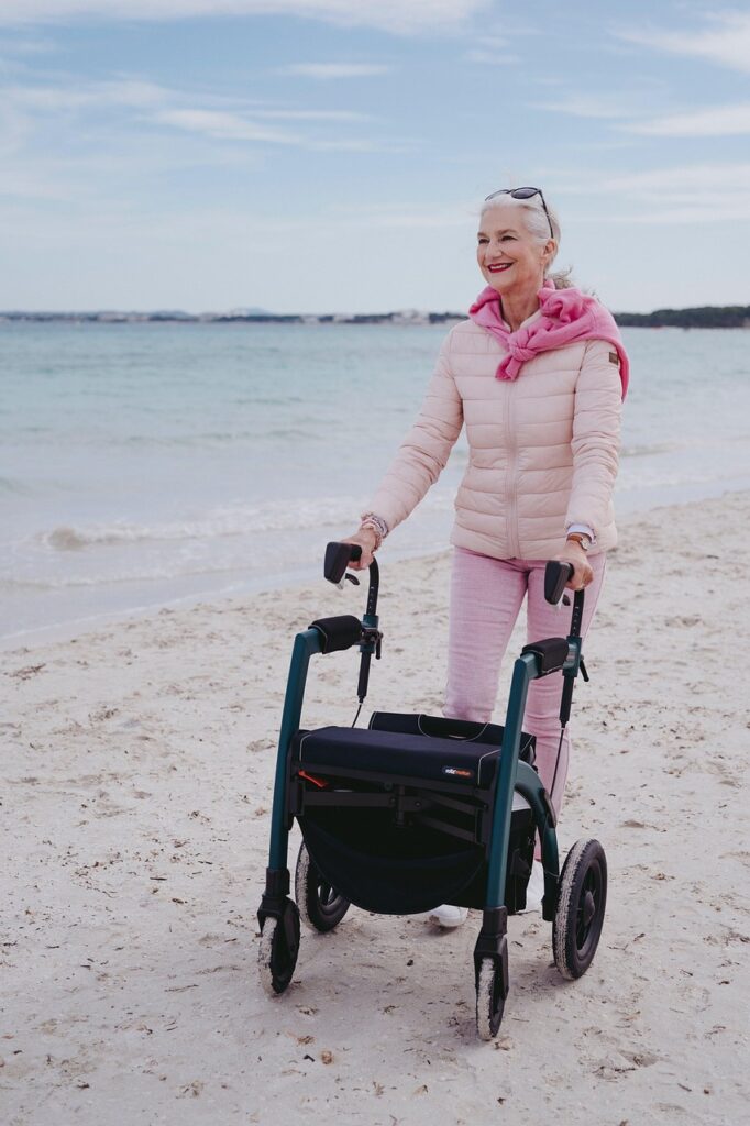 Smiling senior woman using a rollator walker on a beach, promoting mobility and independence